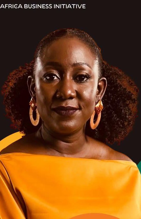 Portrait of Norah Magero in a yellow off-shoulder dress and gold earrings.